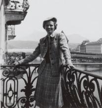 Felice Stampfle standing on a balcony with a river scene behind her.